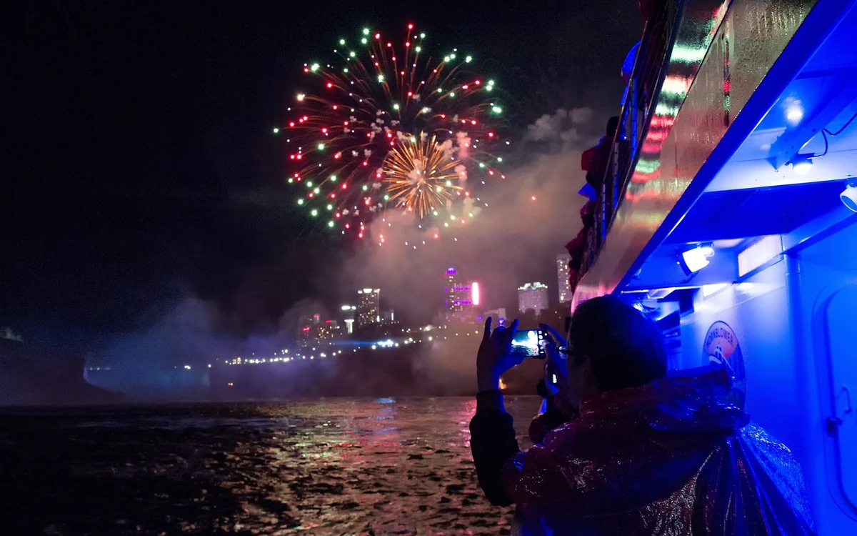 Fireworks bursting above the illuminated Niagara Falls at night