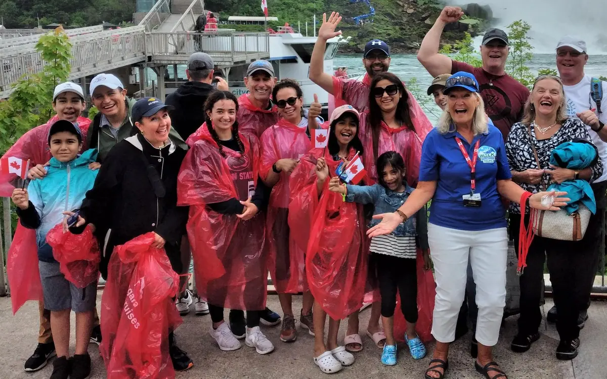 Passengers in red ponchos crowded on the deck of a boat below Niagara Falls
