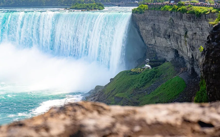 The green curve of Horseshoe Falls seen from a rocky ledge with mist rising off the water